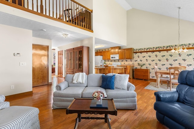 6266 Misty Cove Ln, Columbus, OH 43231 - living area with high vaulted ceiling, light wood-type flooring, a chandelier, and baseboards