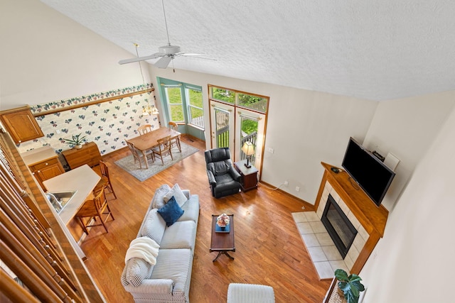 6266 Misty Cove Ln, Columbus, OH 43231 - living area with a textured ceiling, light wood finished floors, a ceiling fan, a tile fireplace, and baseboards