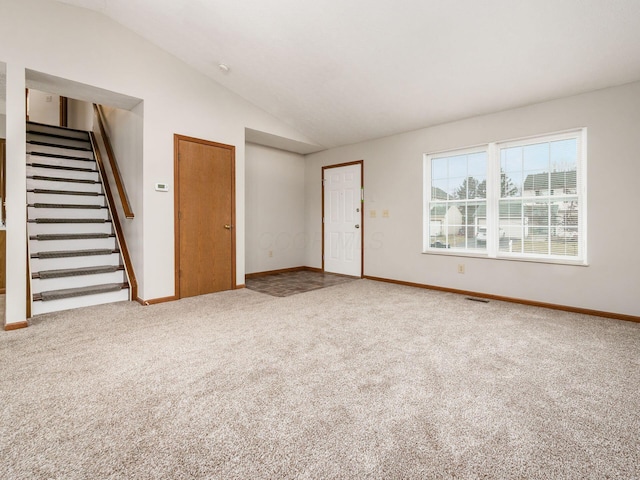 interior space with carpet flooring, visible vents, baseboards, vaulted ceiling, and stairs