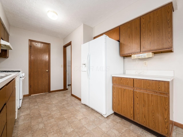 kitchen featuring brown cabinets, light countertops, a textured ceiling, white appliances, and under cabinet range hood