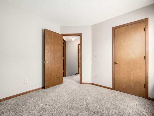 unfurnished bedroom featuring a textured ceiling, baseboards, and carpet flooring