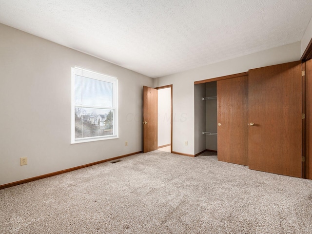 unfurnished bedroom featuring a closet, visible vents, a textured ceiling, and baseboards