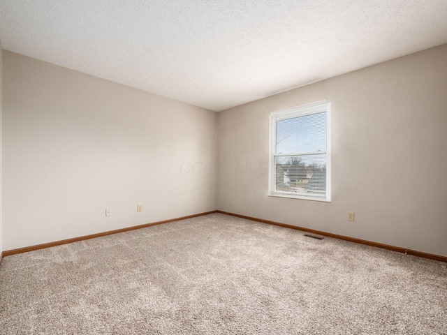 carpeted empty room featuring visible vents, a textured ceiling, and baseboards