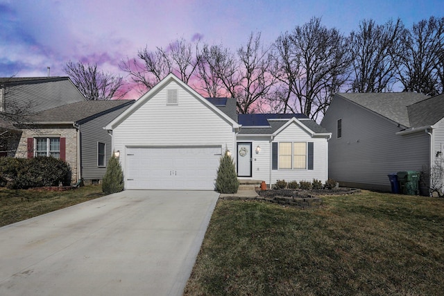 ranch-style house with concrete driveway, a lawn, an attached garage, and solar panels