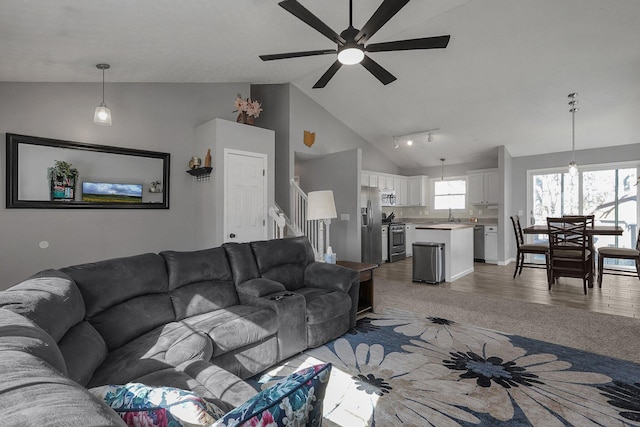 living room with high vaulted ceiling, a ceiling fan, stairway, and wood finished floors