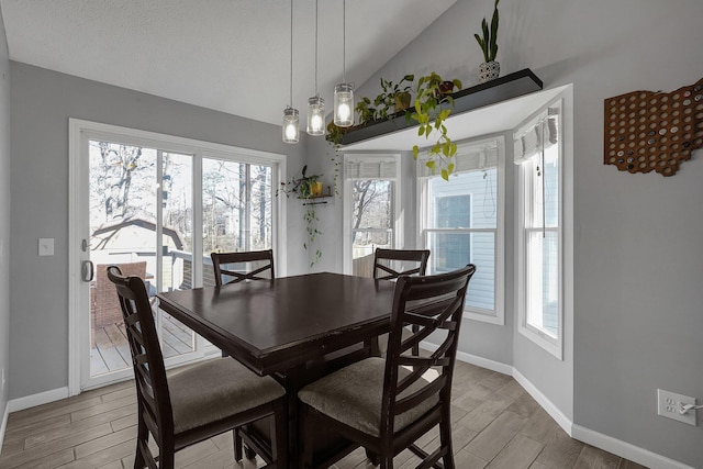 dining area featuring vaulted ceiling, baseboards, and wood finished floors