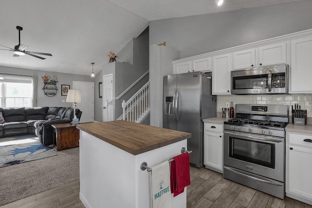 kitchen with white cabinetry, vaulted ceiling, appliances with stainless steel finishes, and open floor plan