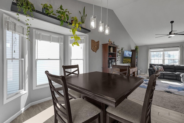 dining space featuring vaulted ceiling, ceiling fan, light wood finished floors, and baseboards