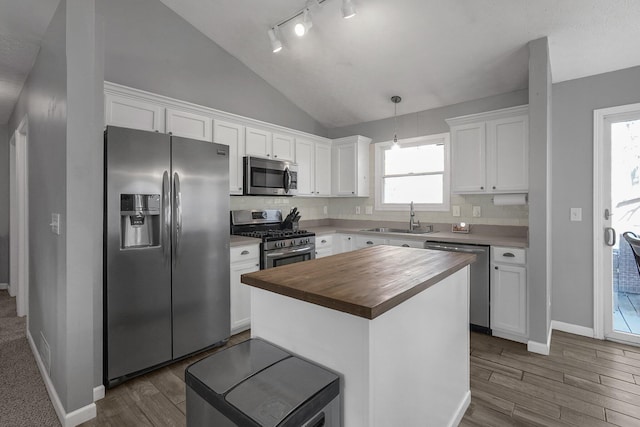 kitchen featuring decorative light fixtures, stainless steel appliances, white cabinets, a sink, and butcher block countertops