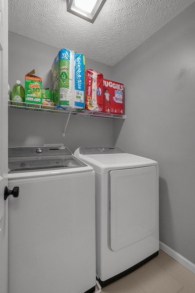 laundry area with a textured ceiling, laundry area, baseboards, and washer and dryer