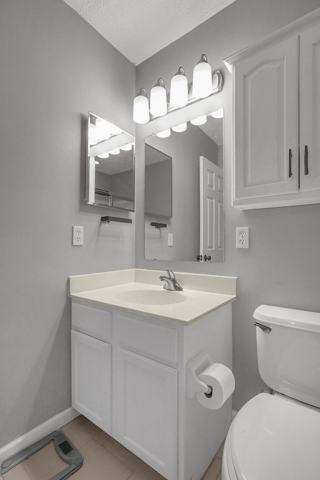 bathroom featuring baseboards, toilet, tile patterned floors, a textured ceiling, and vanity