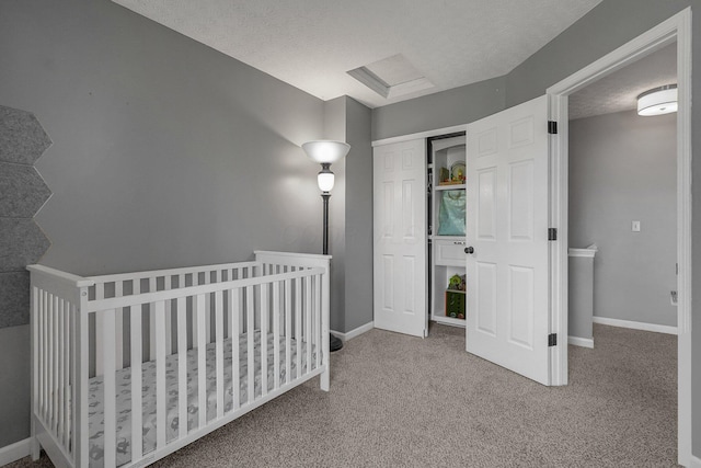 bedroom with attic access, baseboards, a textured ceiling, carpet floors, and a closet