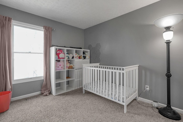 carpeted bedroom with a nursery area, visible vents, a textured ceiling, and baseboards