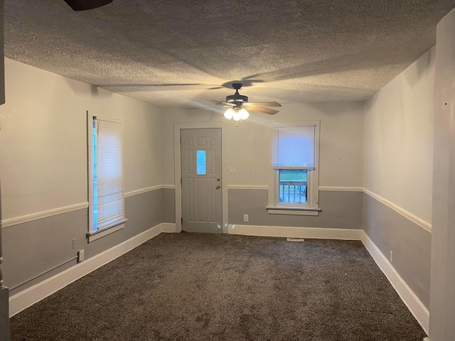 carpeted foyer entrance featuring ceiling fan, baseboards, and a textured ceiling