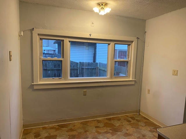 spare room with a textured ceiling and baseboards