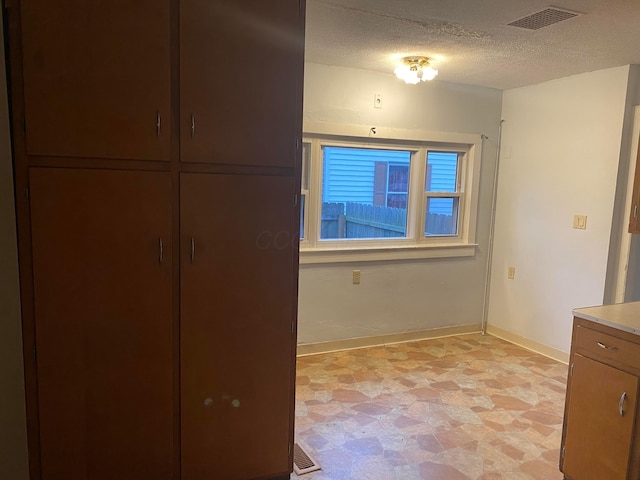 unfurnished bedroom featuring visible vents, a textured ceiling, and baseboards