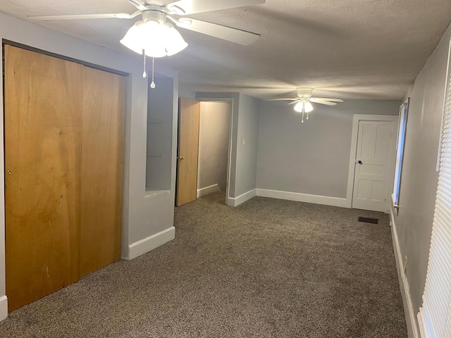 unfurnished room featuring visible vents, baseboards, ceiling fan, dark colored carpet, and a textured ceiling