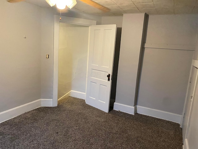 spare room featuring dark carpet and baseboards