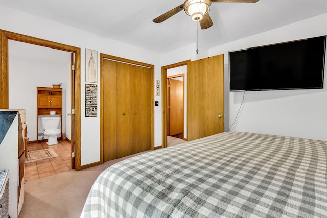 bedroom with light tile patterned floors, a ceiling fan, ensuite bath, a closet, and light colored carpet