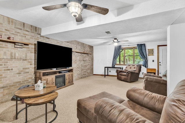 carpeted living area with brick wall, ceiling fan, baseboards, a glass covered fireplace, and a textured ceiling