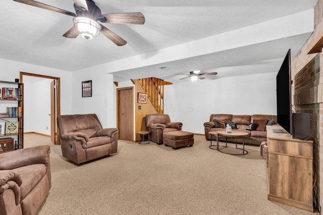 living area with ceiling fan, stairway, carpet, and a textured ceiling