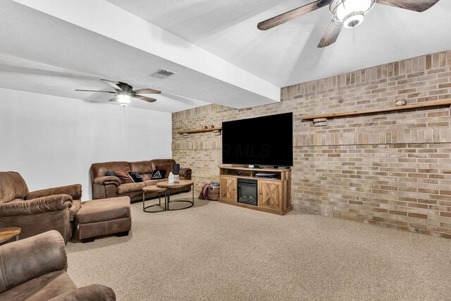 carpeted living area featuring visible vents, brick wall, a fireplace, ceiling fan, and a textured ceiling