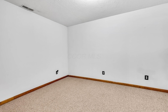 carpeted empty room with visible vents, baseboards, and a textured ceiling