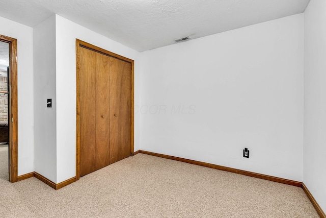 unfurnished bedroom with visible vents, a textured ceiling, a closet, carpet, and baseboards