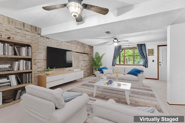 living room featuring visible vents, brick wall, carpet floors, ceiling fan, and a textured ceiling