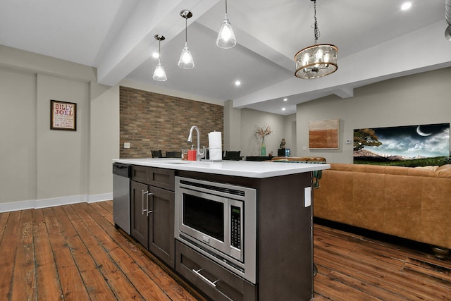 kitchen featuring light countertops, hanging light fixtures, appliances with stainless steel finishes, dark wood-type flooring, and open floor plan