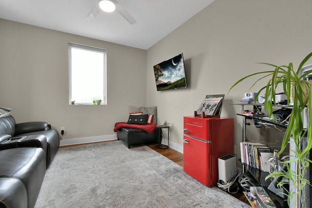 living area featuring baseboards, a ceiling fan, and wood finished floors