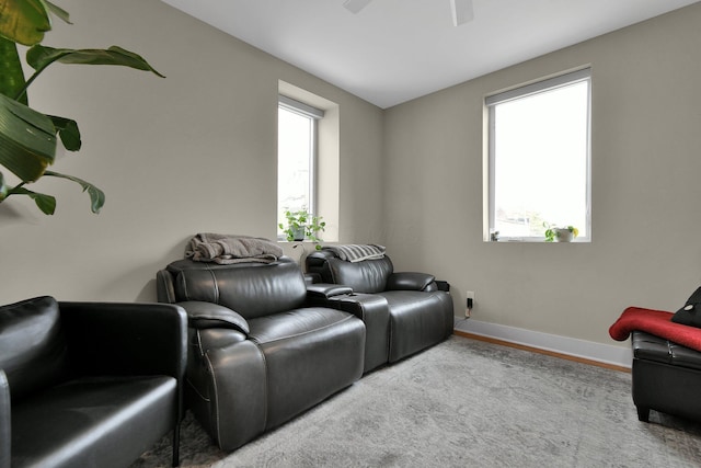 home theater featuring a ceiling fan, a healthy amount of sunlight, baseboards, and wood finished floors