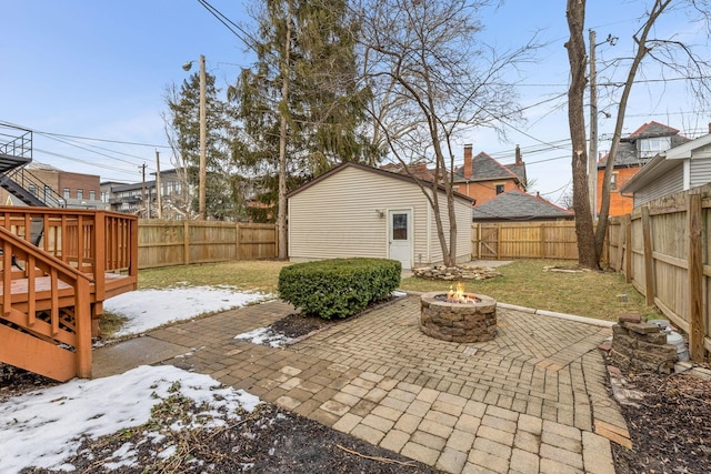 snow covered patio with a yard, a fenced backyard, a fire pit, and a wooden deck