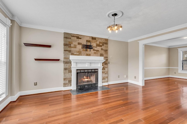 unfurnished living room featuring ornamental molding, plenty of natural light, a fireplace, and wood finished floors