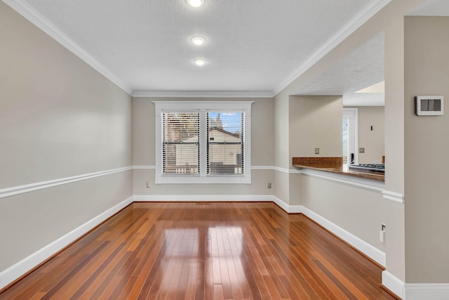 empty room featuring ornamental molding, wood finished floors, and baseboards