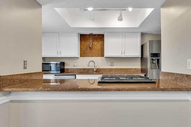 kitchen featuring white cabinets, a raised ceiling, stainless steel appliances, a textured ceiling, and a sink