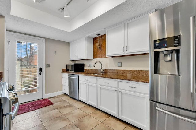 kitchen with appliances with stainless steel finishes, dark stone counters, white cabinets, and light tile patterned floors