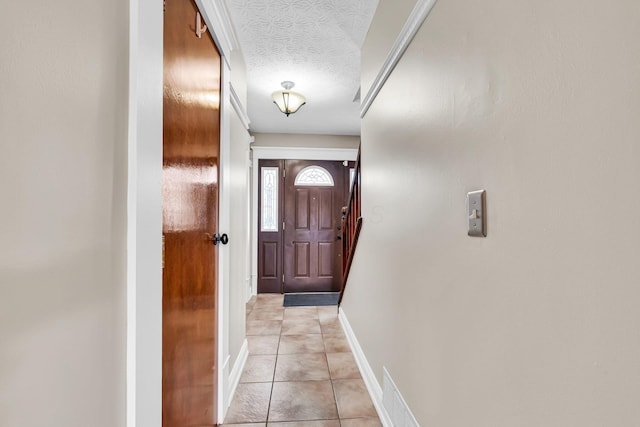 entryway featuring light tile patterned floors, a textured ceiling, and baseboards