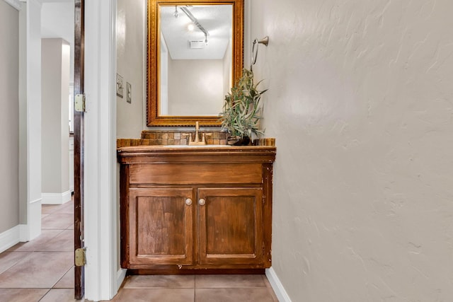 bathroom with vanity, baseboards, track lighting, and tile patterned floors