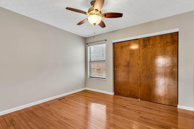 unfurnished bedroom with baseboards, a textured ceiling, a closet, and light wood-style floors