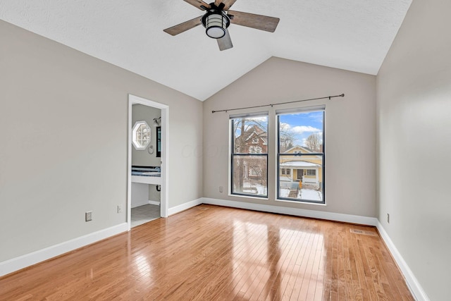 unfurnished bedroom featuring light wood-style floors, vaulted ceiling, baseboards, and a ceiling fan