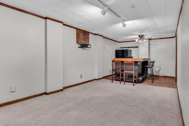 interior space with a dry bar, baseboards, a ceiling fan, crown molding, and track lighting