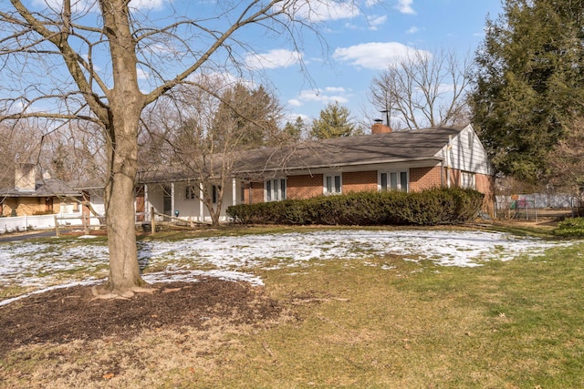 view of front of home featuring a yard, brick siding, and a chimney