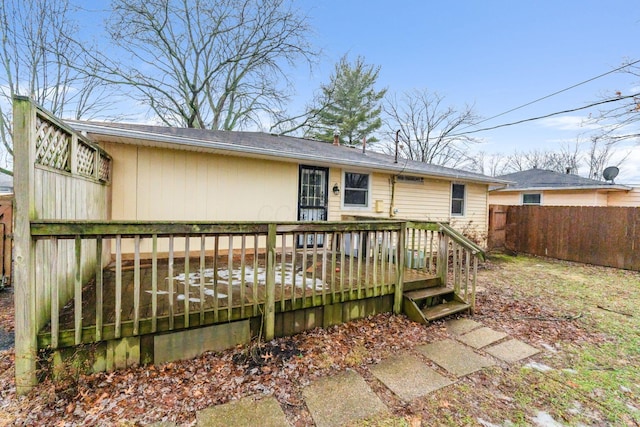 rear view of property featuring a deck and fence