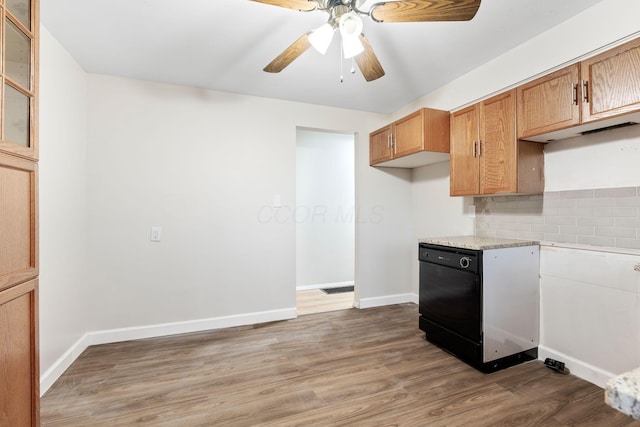 kitchen featuring light countertops, decorative backsplash, glass insert cabinets, wood finished floors, and baseboards