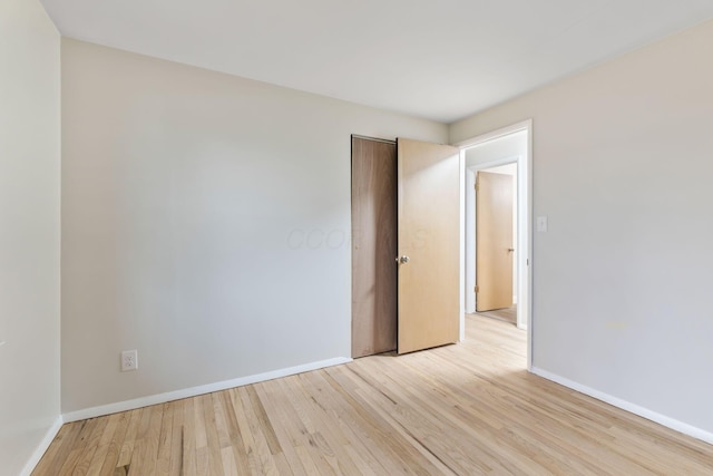 empty room featuring light wood-type flooring and baseboards