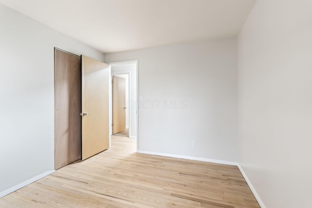 unfurnished room with light wood-style flooring and baseboards