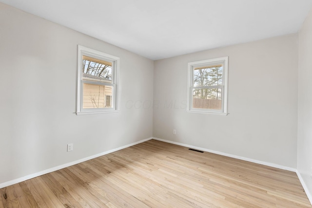 spare room featuring baseboards, visible vents, and light wood-style floors