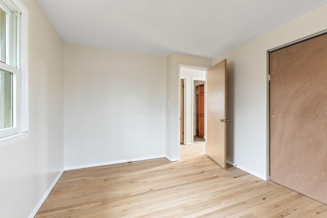 unfurnished bedroom with light wood-style floors, a closet, and baseboards