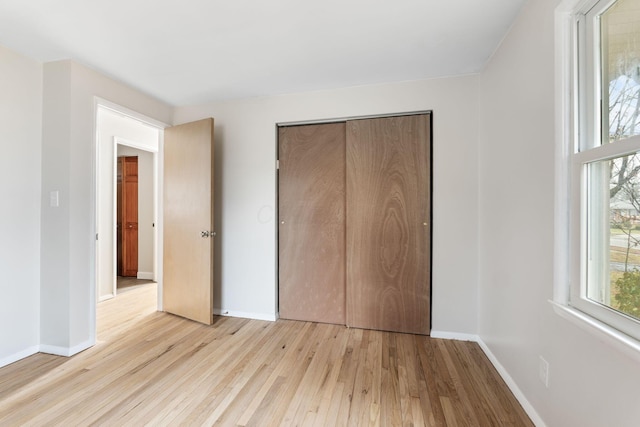 unfurnished bedroom featuring baseboards, a closet, and light wood-style floors